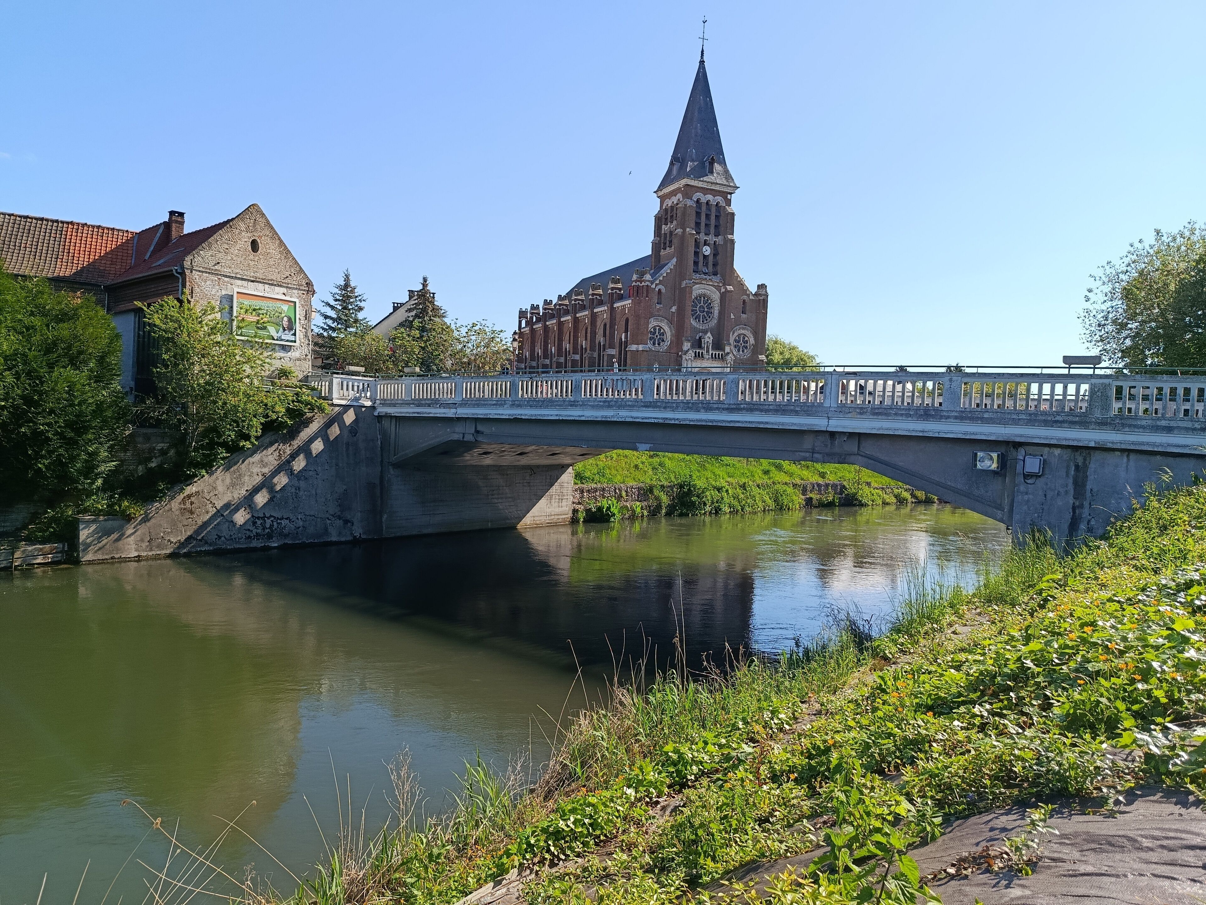 Een stenen brug over een rustige rivier, met een kerk op de achtergrond.