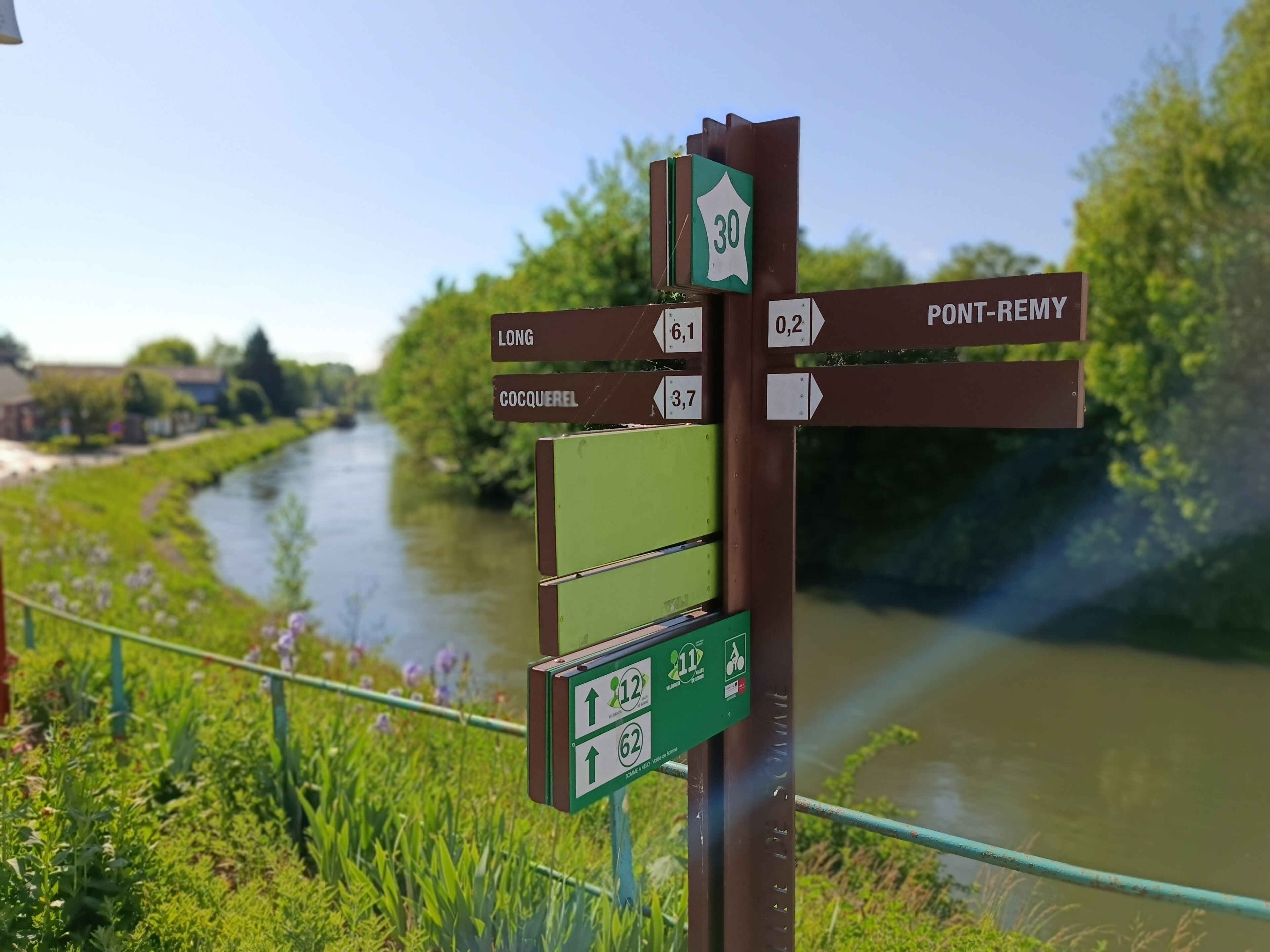 A directional signpost with distance markers to Long, COCQUEREL, and Pont-Remy.