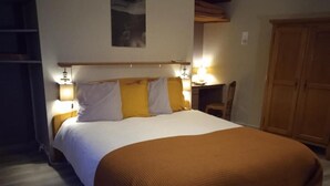 Une chambre avec un grand lit, deux lampes de chevet, une armoire en bois et une chaise.