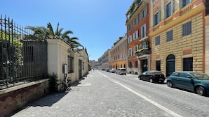A cobblestone street lined with historic buildings, bicycles parked along the sidewalk, and cars parked on the side of the road. - Room-foro Romano Apartments C (Rome)