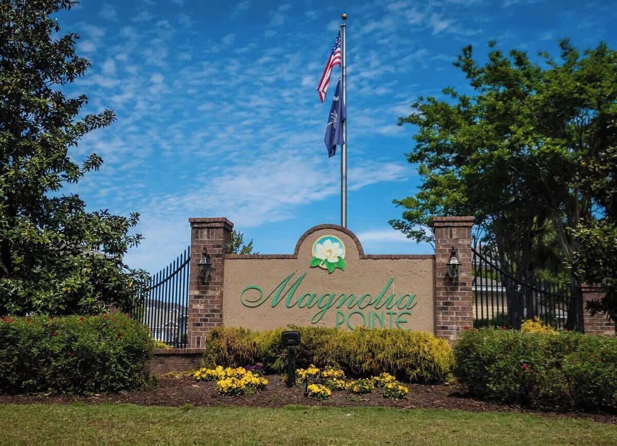 A brick entrance with a sign reading "Magnolia Pointe" and an American flag.