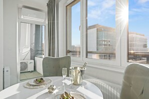 A hotel room with a balcony, a dining table set with plates, glasses, and a champagne bucket. - Pure Home Premium Apartments (Wroclaw)