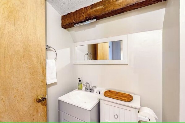 Ein Badezimmer mit einem weißen Waschbecken, einer Holzauslage und einem Spiegel darüber.