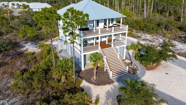 A two-story beachfront house with a covered porch and a staircase leading to the entrance. - Home Away From Home (Port St. Joe)