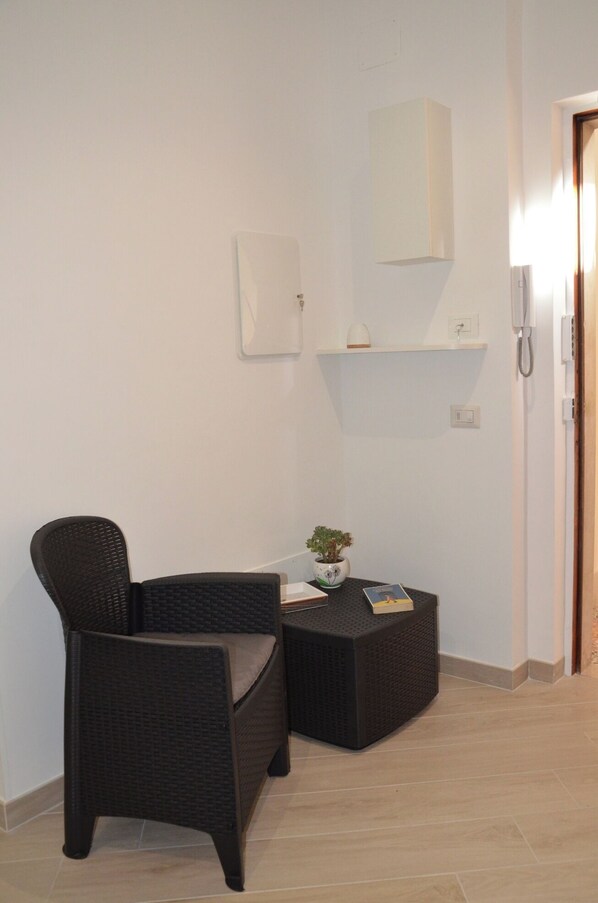 A corner room with a wicker chair, a small table with a plant, and a phone on the wall. - Sweet Emily, Panoramic comfort just a stone's throw from Sorrento! (Sant'Agnello)