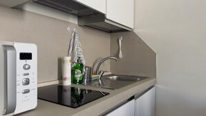 A compact kitchen with a built-in microwave, a sink, and a stainless steel faucet.