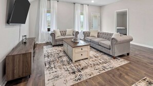 A modern living room with a sofa set, a coffee table, and a TV mounted on the wall.