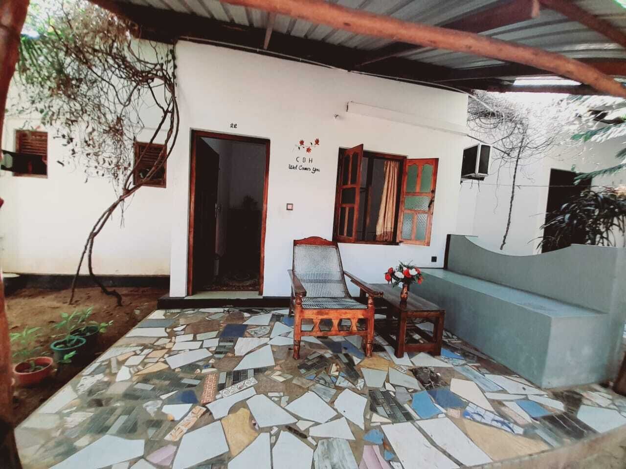 A room with a mosaic floor, a wooden chair, a sofa, and a door leading outside.