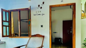 A room with a wooden chair, a window with a curtain, a wall with a CBH logo and a door marked with the number 25.