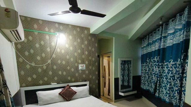 Een hotelkamer met een bed, een plafondventilator, een luchtkoeler aan de muur en kamer met een patroon.