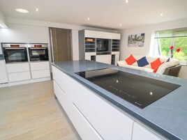 A modern kitchen with built-in appliances, white cabinetry, and a grey countertop.