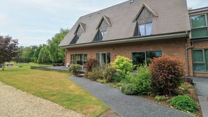 Un bâtiment moderne à deux étages, doté d’un toit en pente, de grandes fenêtres et d’une allée en gravier menant à l’entrée.