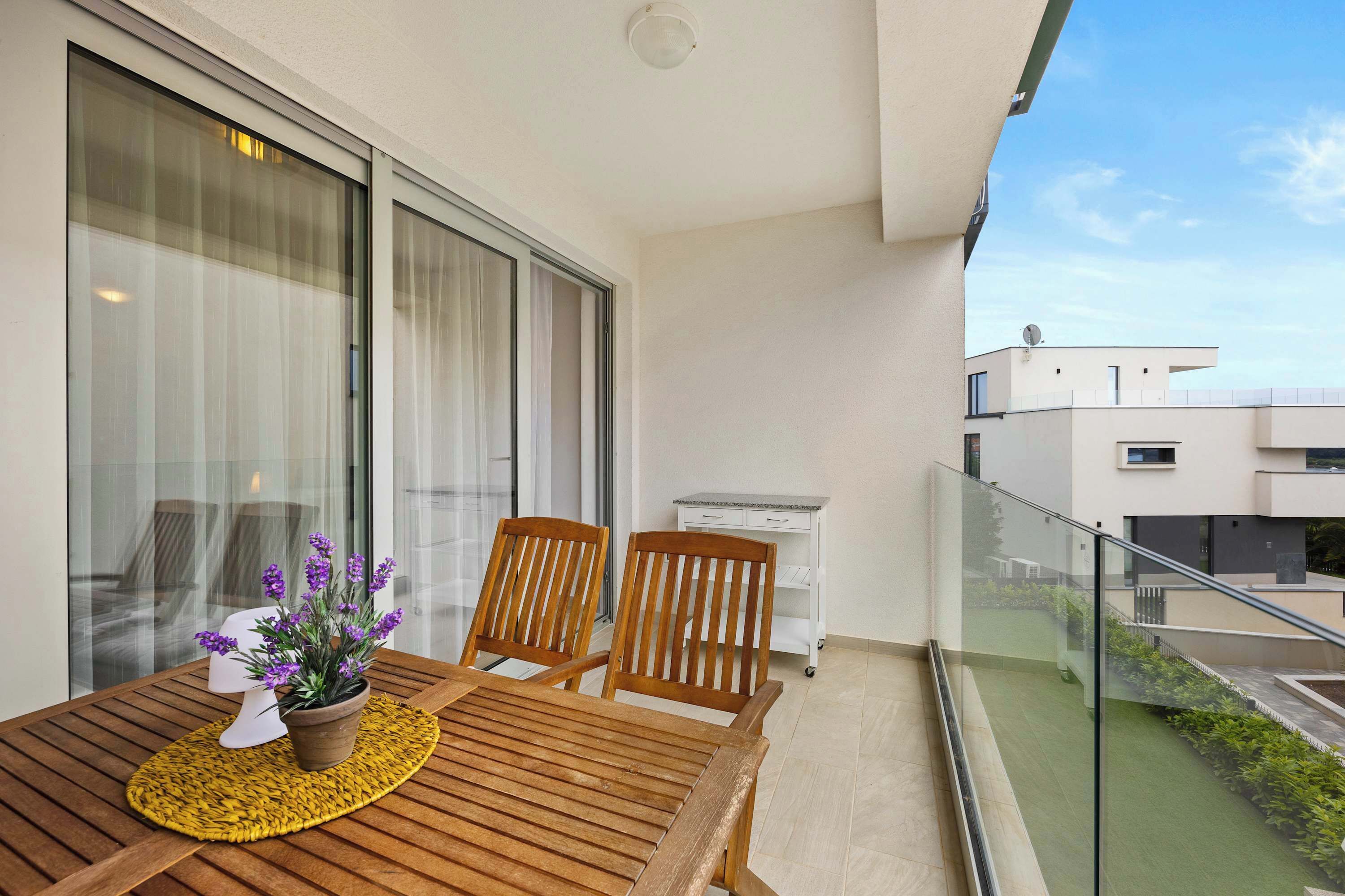 Ein Balkon mit einem Holztisch, zwei Stühlen und einem Blumentopf.