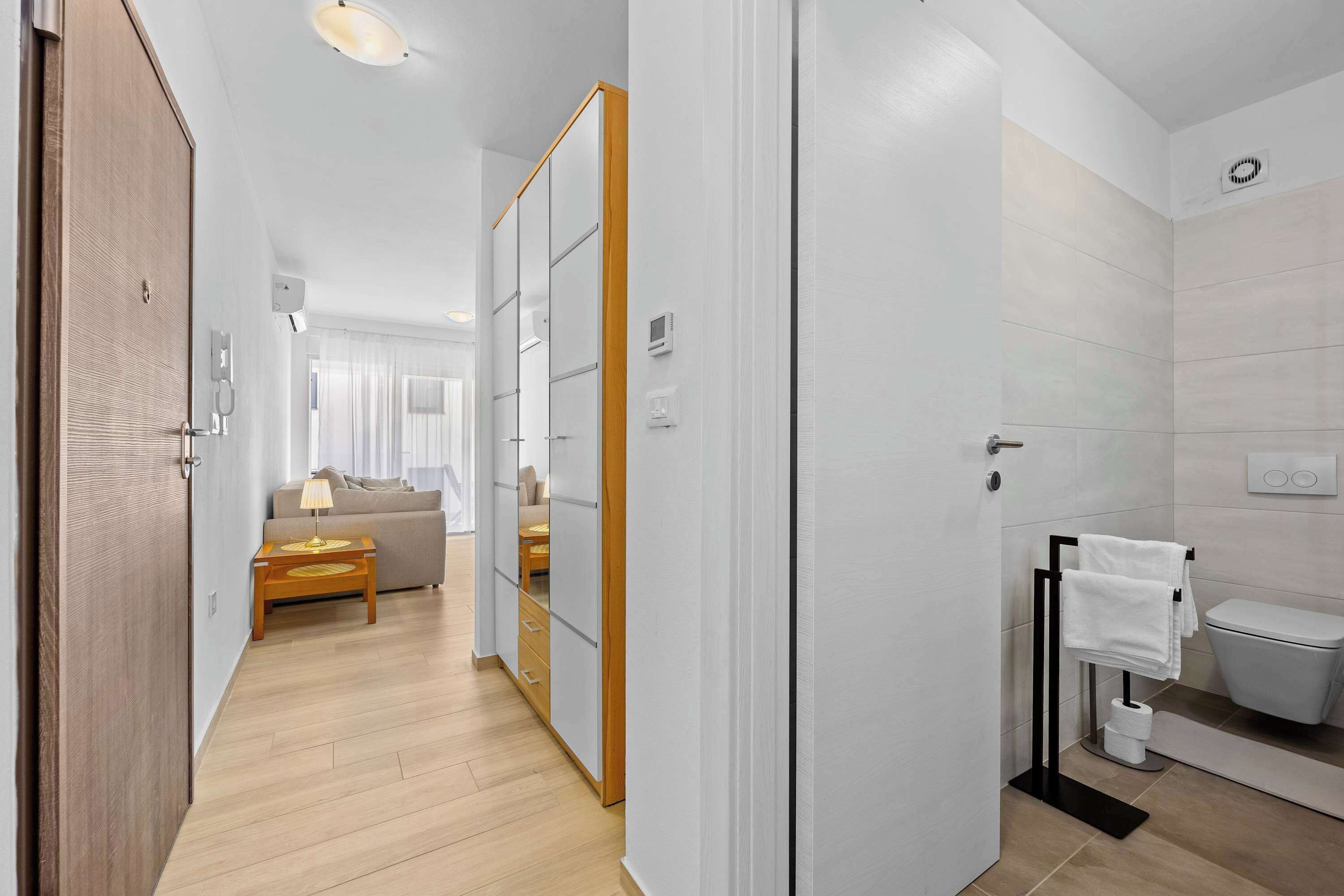 Un baño moderno con inodoro, lavamanos y perchero para toallas.