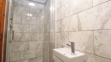 Un baño con ducha, lavamanos e inodoro.