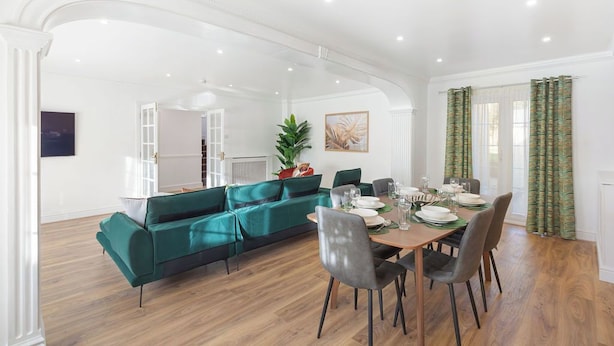 Een eethoek met een houten tafel voor vier personen, omringd door groene gestoffeerde banken.