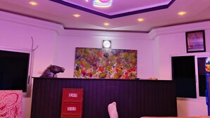 A room with a ceiling light fixture, a painting, a sculpture, and a sign with the word 'SOFIEBRA'.