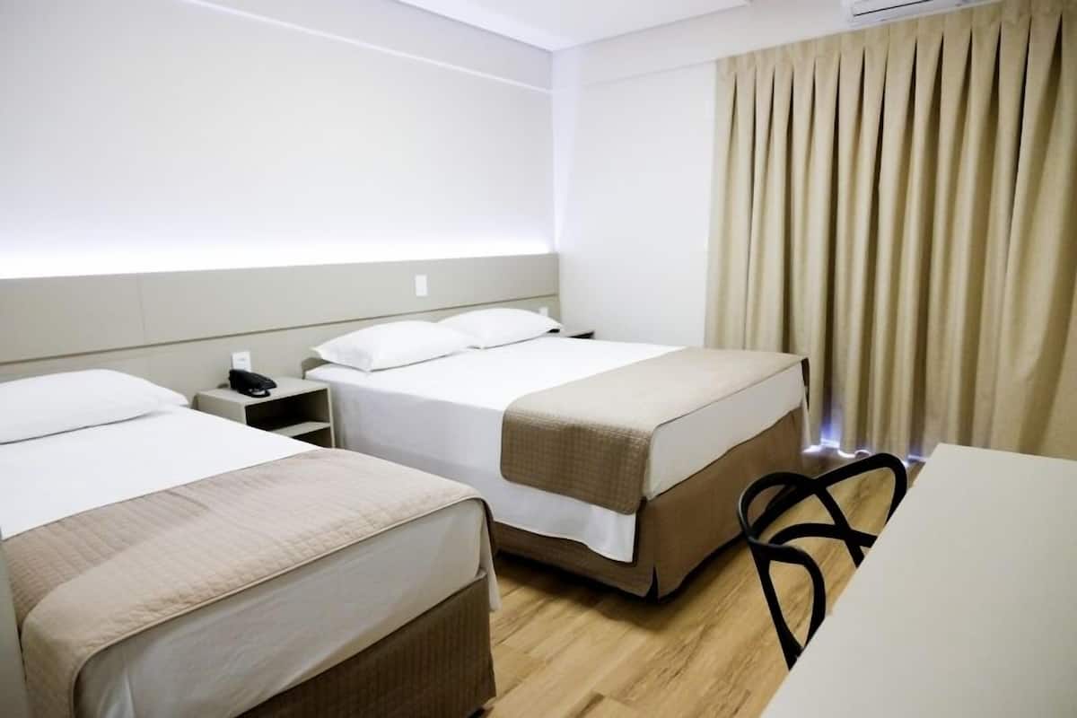 A hotel room with two beds, a desk, and a chair.