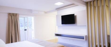 A modern hotel room with a bed, a TV mounted on the wall, and a sliding door.