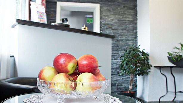 A clear glass bowl with apples on a table. - Adolph*s.hotel (Cologne)