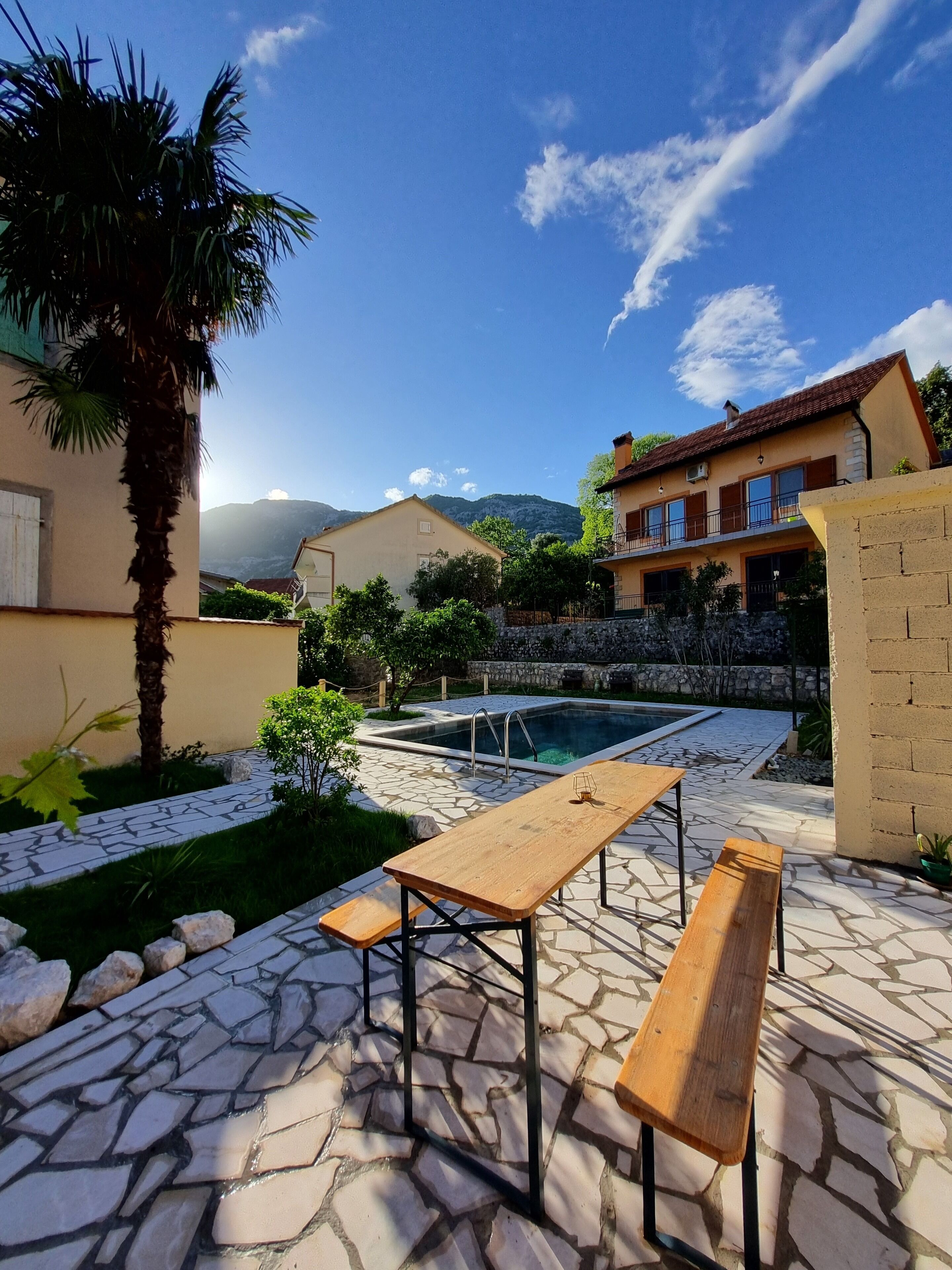 A pool area with stone flooring, a wooden table, and benches.