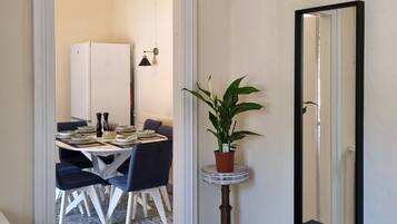 Um corredor com área de jantar, planta em vaso, um banco e um espelho.