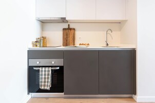 Una cucina moderna con forno integrato, lavello e tagliere di legno sul piano di lavoro.