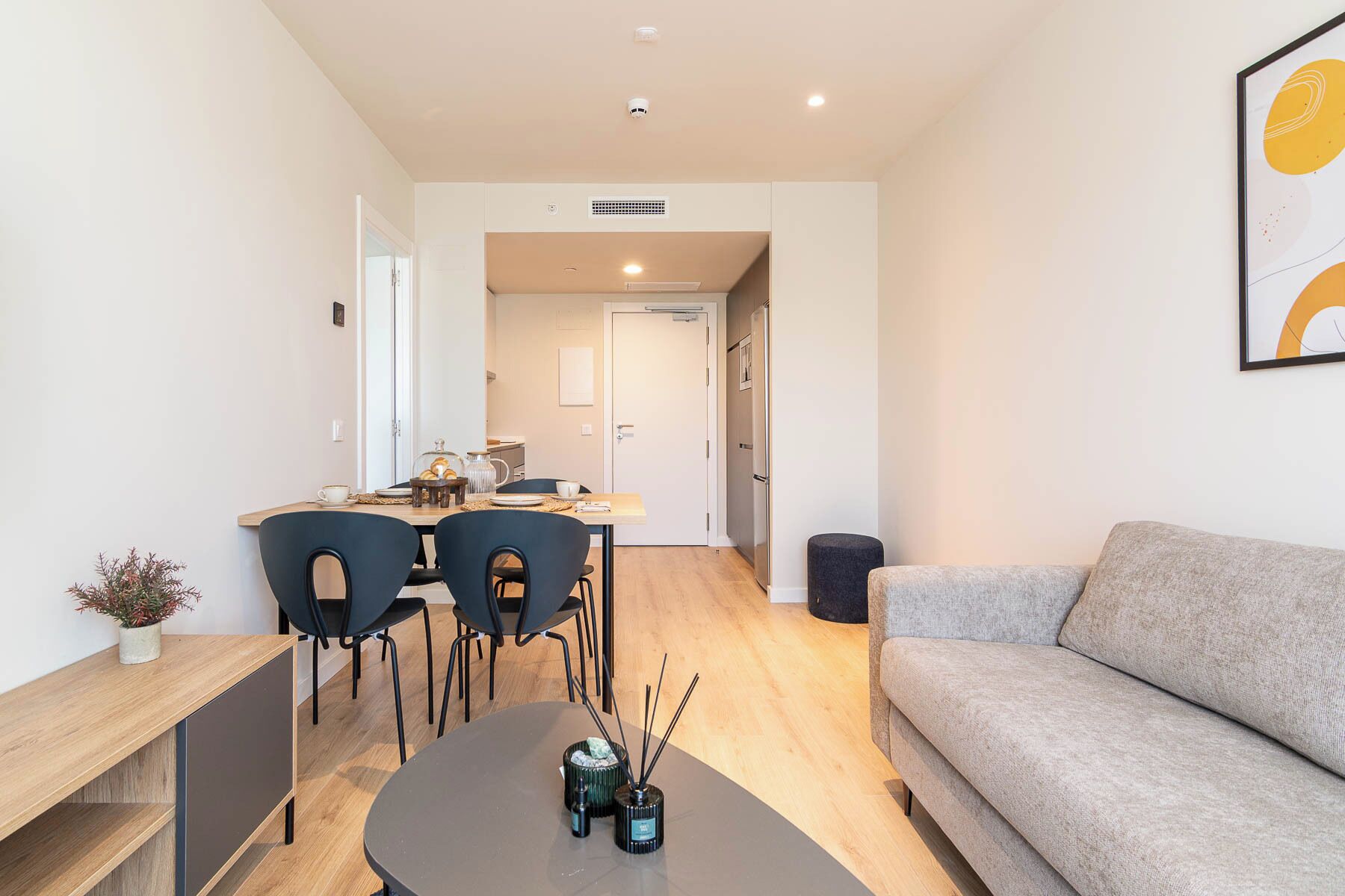 Un salon moderne avec un canapé gris, une table basse et un coin repas comprenant des chaises et une table.