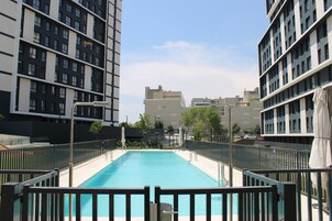 Una piscina rodeada de edificios altos, con un cielo despejado.