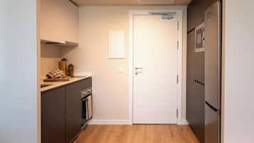 Una cocina compacta con suelo de madera, una puerta blanca y un refrigerador.