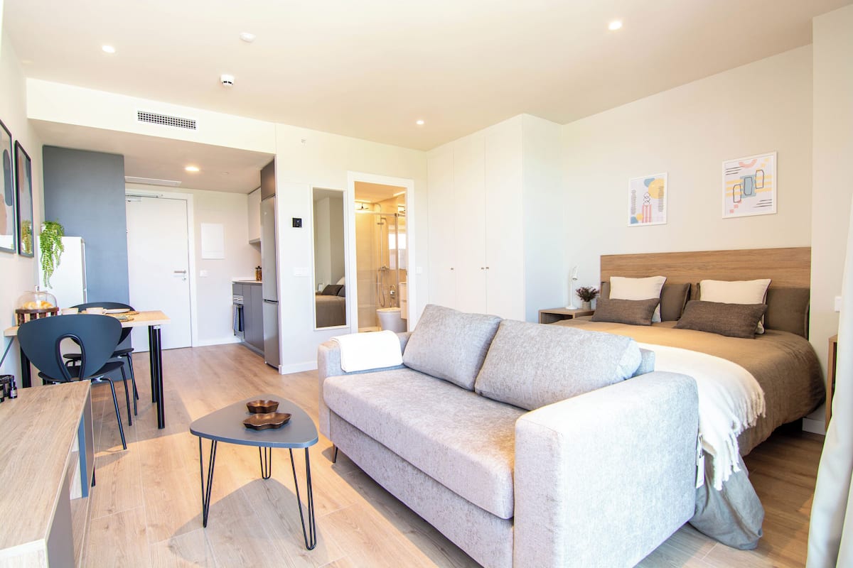 A modern living room with a sofa, a small table, and a bed.