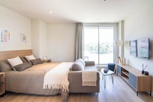 Ein modernes Hotelzimmer mit einem großen Bett, einer Couch, einem kleinen Tisch und einem Fernseher.