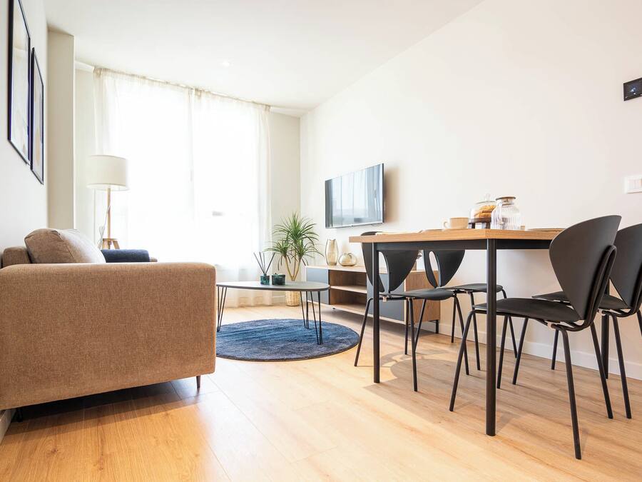 A modern living room with a sofa, a dining table with chairs, a TV, and a coffee table.