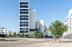 Eine moderne Stadtstraße mit mehrstöckigen Wohnhäusern, blauem Himmel und einer Fahrbahn mit Pfeilen.