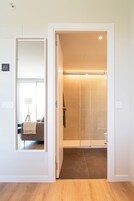 A modern bathroom with a glass shower enclosure, a visible toilet, and a towel hanging on the wall.