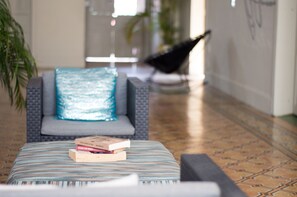 A modern lounge area with a patterned ottoman, a blue cushioned chair, and a black chair in the background. - Hotel México Mazatlán (Mazatlán)