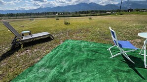 Un espacio al aire libre con césped artificial verde, una silla de metal y una pequeña mesa.
