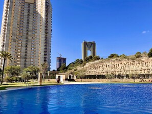 Un barrio residencial con piscina, un edificio de apartamentos alto y una estructura distintiva con forma de puente.