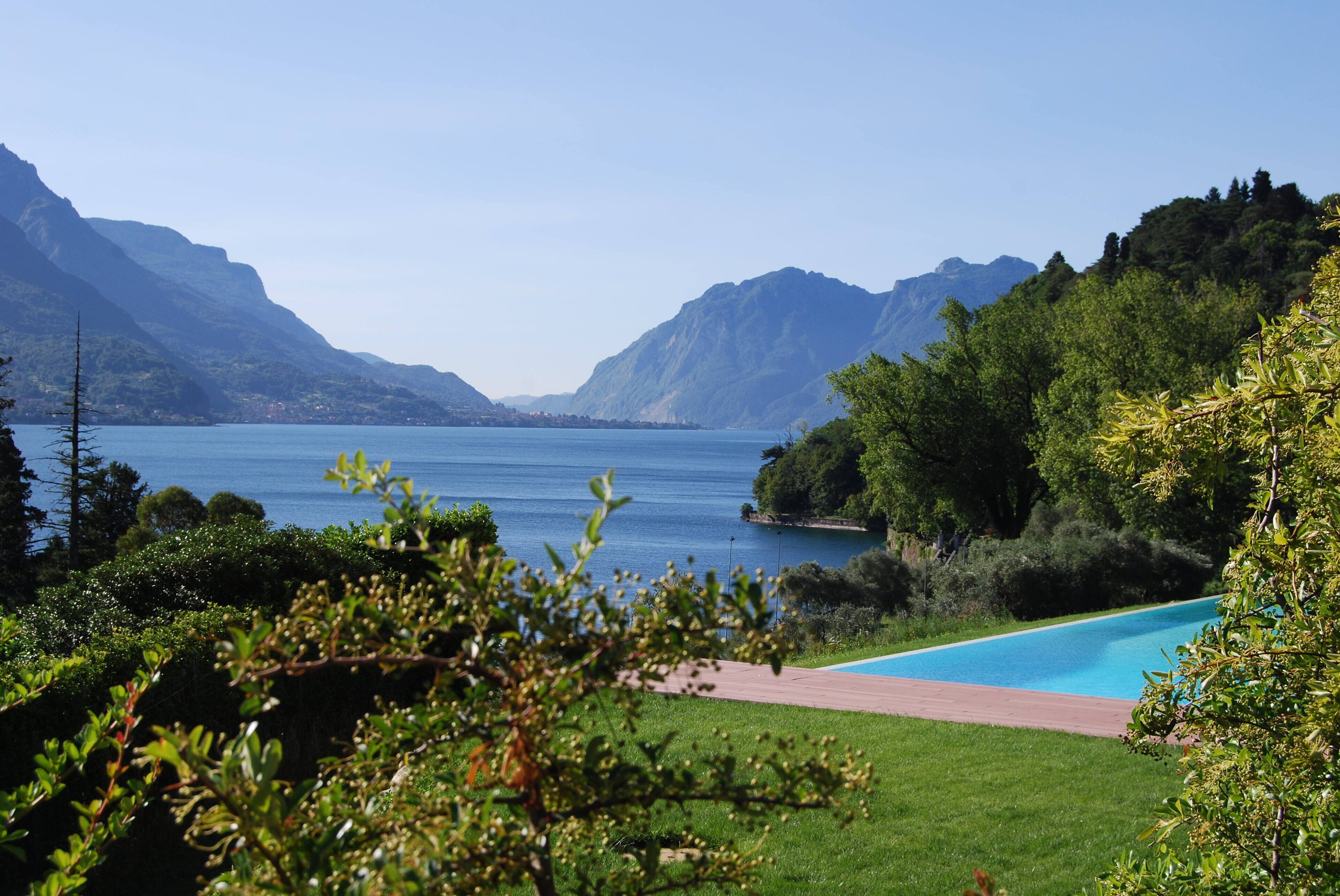Vista de un lago con montañas al fondo y una piscina al frente.