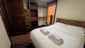 Une chambre d’hôtel avec un grand lit, une armoire et une petite table.
