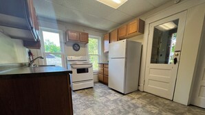 Une cuisine avec des meubles de rangement en bois, un réfrigérateur blanc, une cuisinière et un évier.