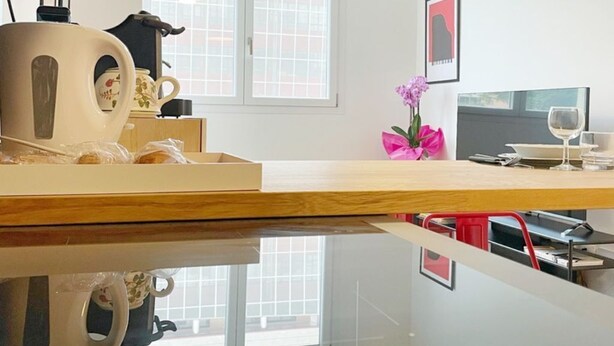 Une cuisine moderne avec un plan de travail en bois, une bouilloire, une machine à café et un vase rempli de fleurs.