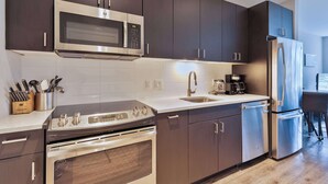 A modern kitchen with dark cabinets, stainless steel appliances, and a white countertop.