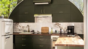 A compact kitchen with dark cabinets, a marble backsplash, and a wooden countertop. - Sunken Escapes #3 Kit's Retreat (Kings County)