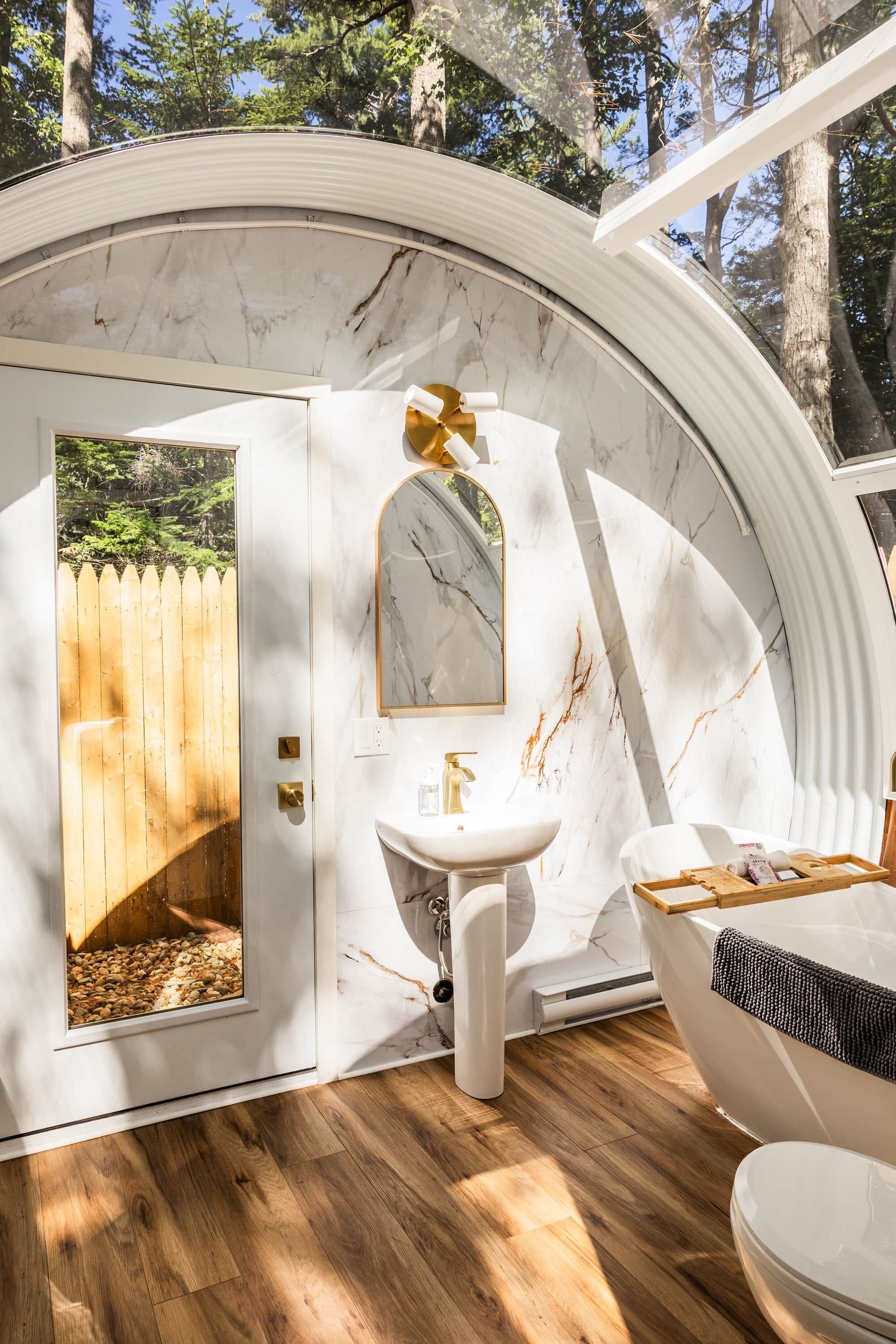 A bathroom with a marble wall, a sink, a mirror, and a bathtub.