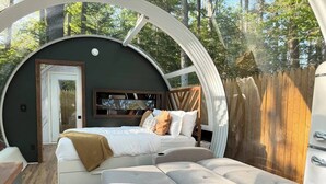 A cozy, circular room with a bed, a sofa, and a small table. - Sunken Escapes #3 Kit's Retreat (Kings County)