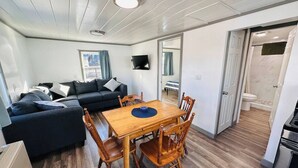 Un espacio habitable compacto con comedor, sofá, televisor y cocina.