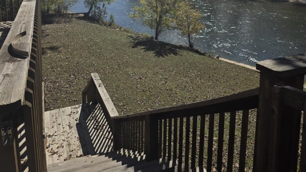 A wooden deck overlooking a river with trees and a clear sky.