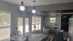 A kitchen with a granite countertop, two pendant lights, a built-in oven, and a dining area with wooden chairs.