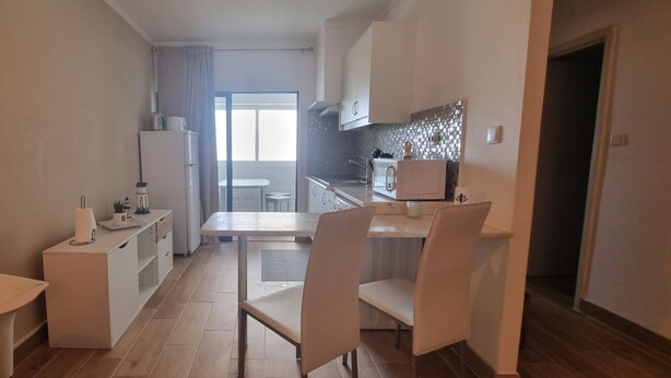 A compact kitchen with a dining area, a refrigerator, a microwave, and a small table with chairs. - Clube Praia da Rocha 3 Great Flat 532 (Portimão)
